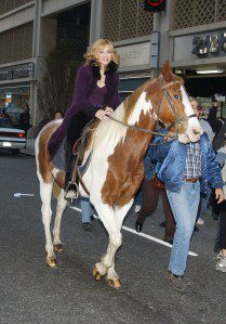 Madonna smiles as she rides a horse outside the 