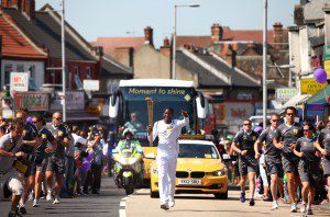 Labrinth carries the Olympic Flame on the Torch Relay leg between Harrow (London Borough) and Brent (London Borough) during Day 68 of the London 2012 Olympic Torch Relay on July 25, 2012 in London, England.