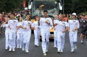 Siva Kaneswaran of The Wanted carries the Olympic Flame with other members of his bank on the Torch Relay leg from Great Wyrley to Leamore on Day 43 of the Olympic Flame Torch Relay on June 30, 2012 in Newton, England.