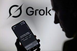 The Grok X AI app is used on a mobile phone with the Grok logo visible in the background in this photo illustration in Brussels, Belgium, on March 8, 2025. (Photo illustration by Jonathan Raa/NurPhoto via Getty Images)